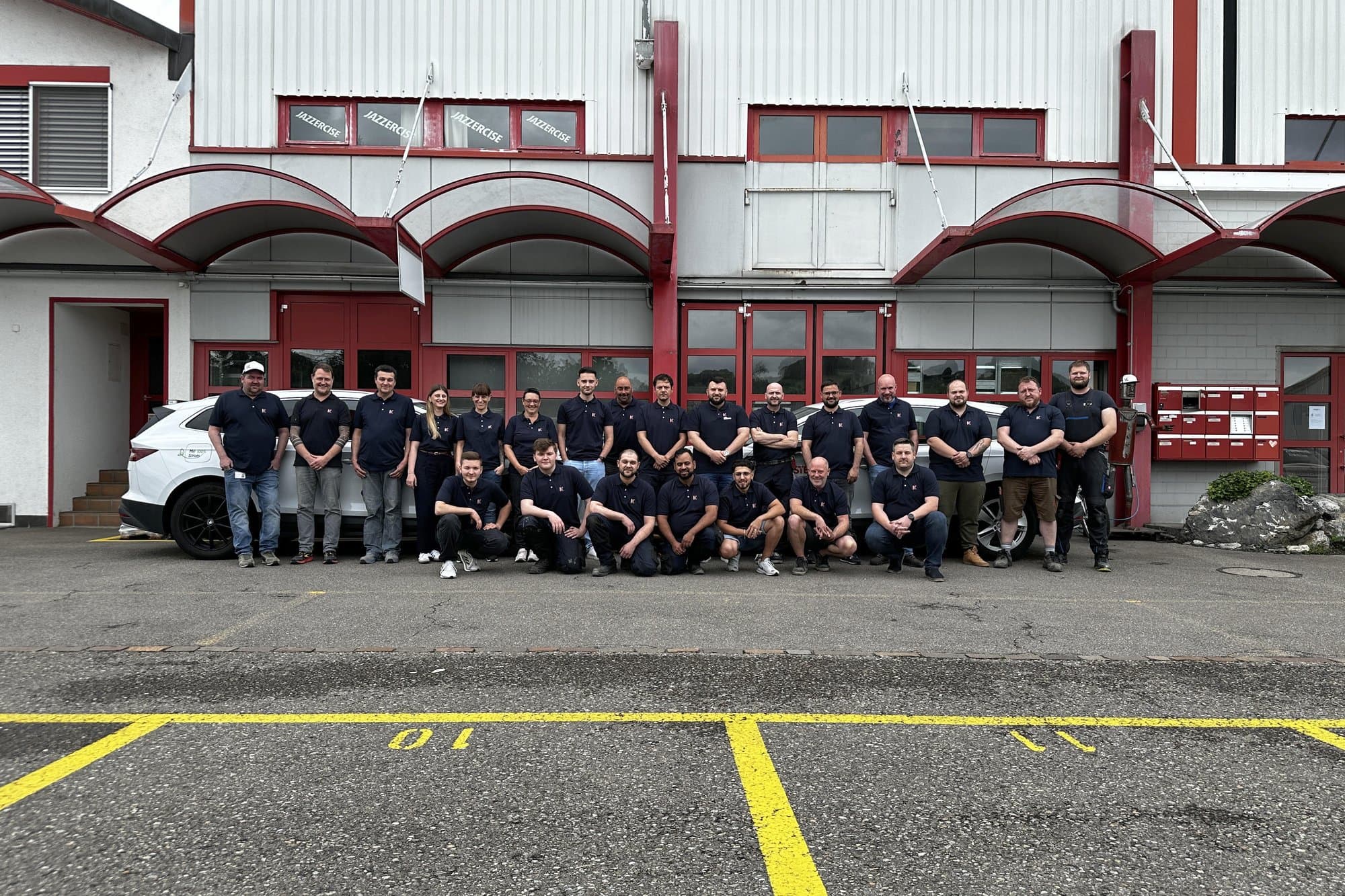 Mitarbeitende der Koster AG vor dem Firmengebäude in Zürich, mit den Servicefahrzeugen.