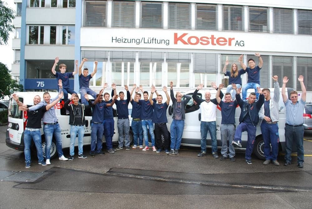 Mitarbeitende der Koster AG vor dem Betriebsgebäude mit den Servicefahrzeugen